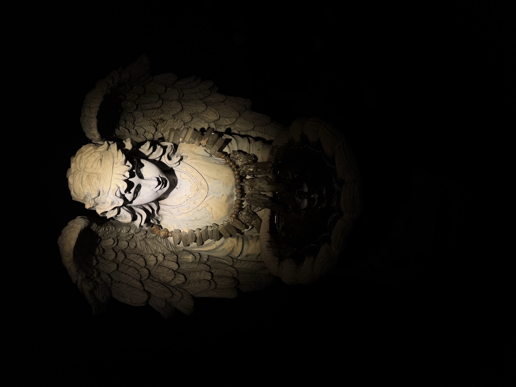 Serafina lit at night with crystals draped around her shoulders and basin.